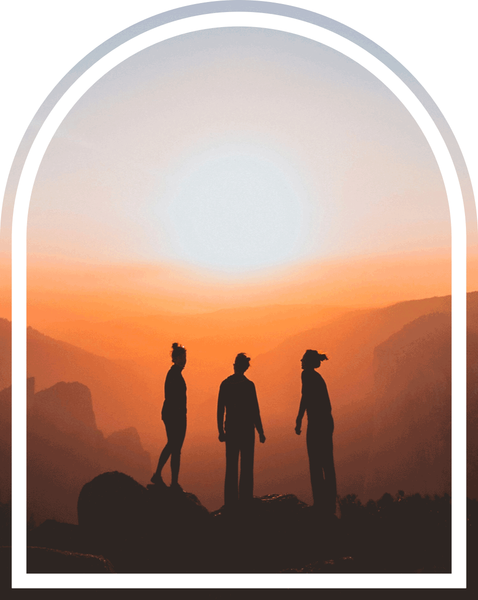 Arched silhouette of three friends, family members on a mountain during sunset.